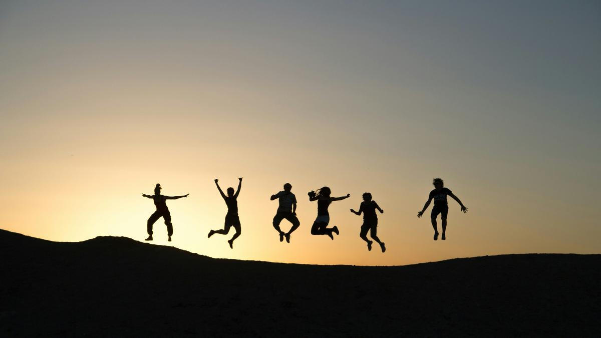 Joyful Shadows at Sunset Silhouettes of six happy people jumping on a mountain at sunset, symbolizing the positive, uplifting 5-star reviews and exceptional service of Princeton Elite Car Service